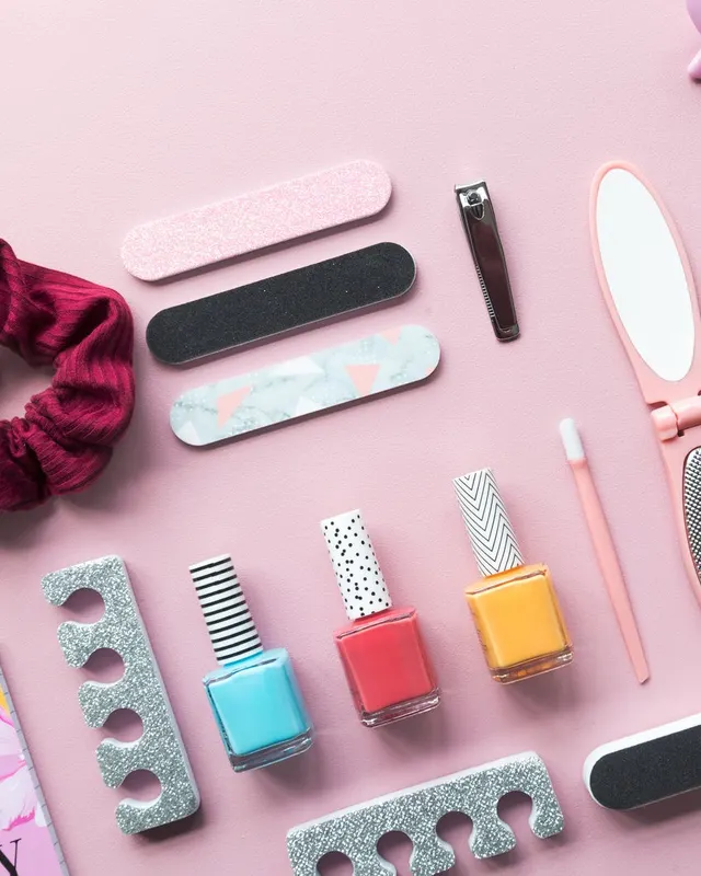 Esmaltes, limas y herramientas de manicura sobre fondo rosado